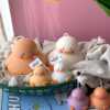 A close-up of four handcrafted duck-shaped candles in soft yellow tones with orange beaks and feet, and pink blushed cheeks, ideal for cute gifts or decorative accents. The candles are labeled with 'Je T’aime Candle' tags and are placed beside a dried floral arrangement, creating a soft, aesthetic backdrop. These adorable soy wax candles are perfect for baby showers, birthday favors, Easter gifts, or aesthetic room decor.