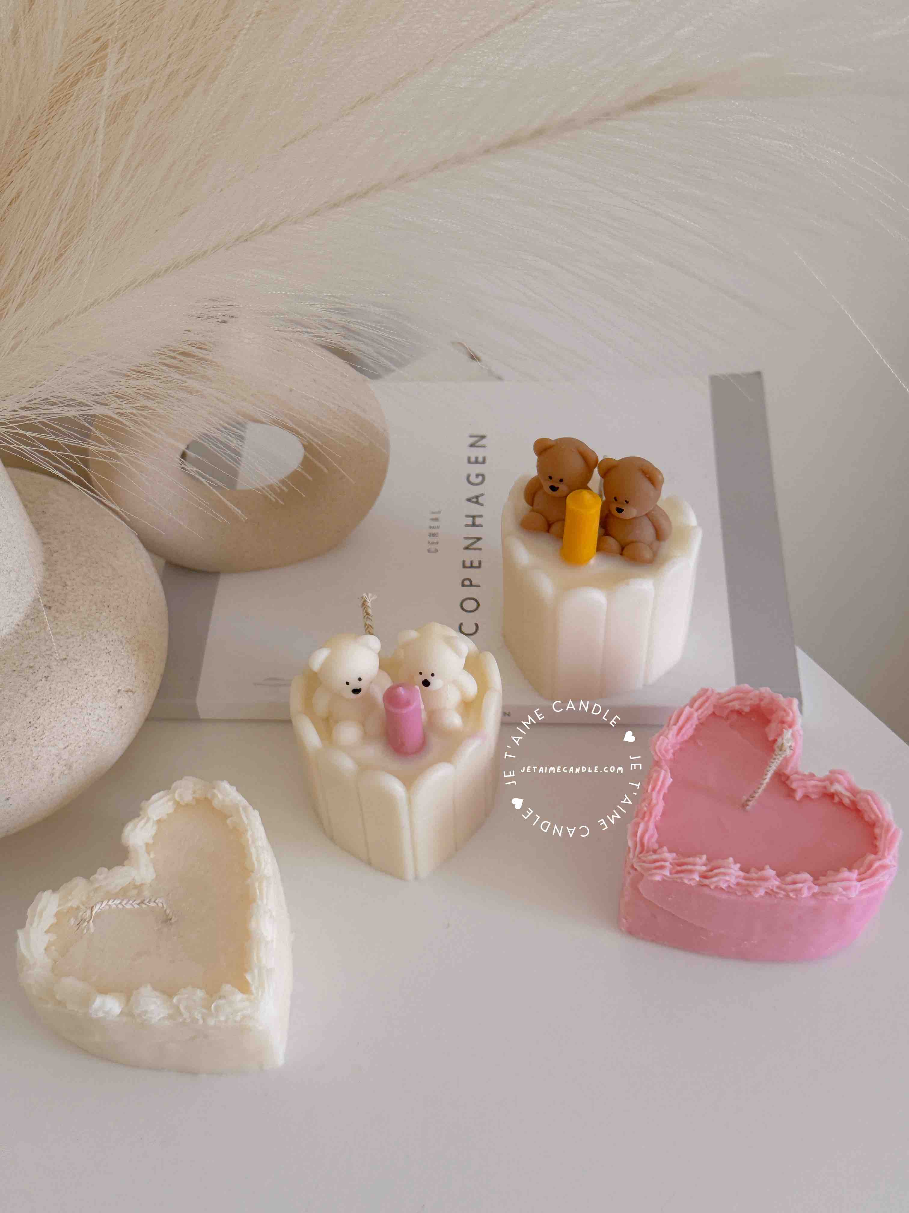 Two small cream white cakes topped with cute baby bear decorations and a colorful birthday candle.