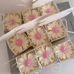Set of handmade daisy-shaped candles with white petals and pink centers, displayed on a fabric surface – perfect for wedding favors, bridal shower gifts, or spring party decorations.