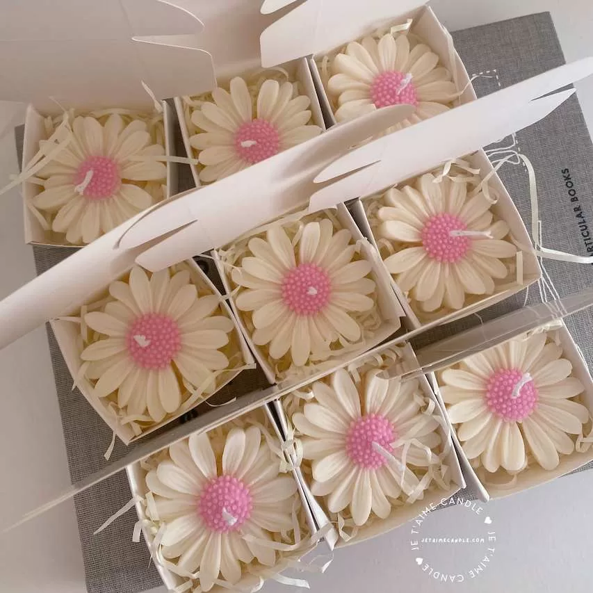 Set of handmade daisy-shaped candles with white petals and pink centers, displayed on a fabric surface – perfect for wedding favors, bridal shower gifts, or spring party decorations.