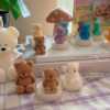 A collection of whimsical handmade bear-shaped candles in soft pastel colors, arranged on a cozy table. Each candle features intricate details. The candles are perfect for nursery decor, gifts, or home accents, adding warmth and charm to any space.