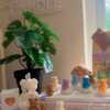 A collection of whimsical handmade bear-shaped candles in soft pastel colors, arranged on a cozy table. Each candle features intricate details. The candles are perfect for nursery decor, gifts, or home accents, adding warmth and charm to any space.