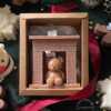 A cozy box featuring a teddy bear surrounded by festive Christmas decorations, perfect for holiday warmth and charm.