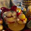 Two ducks in candle cozy scarves resting on a wooden board, ideal for unique holiday decor and gift inspiration.
