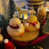 Two ducks in candle cozy scarves resting on a wooden board, ideal for unique holiday decor and gift inspiration.