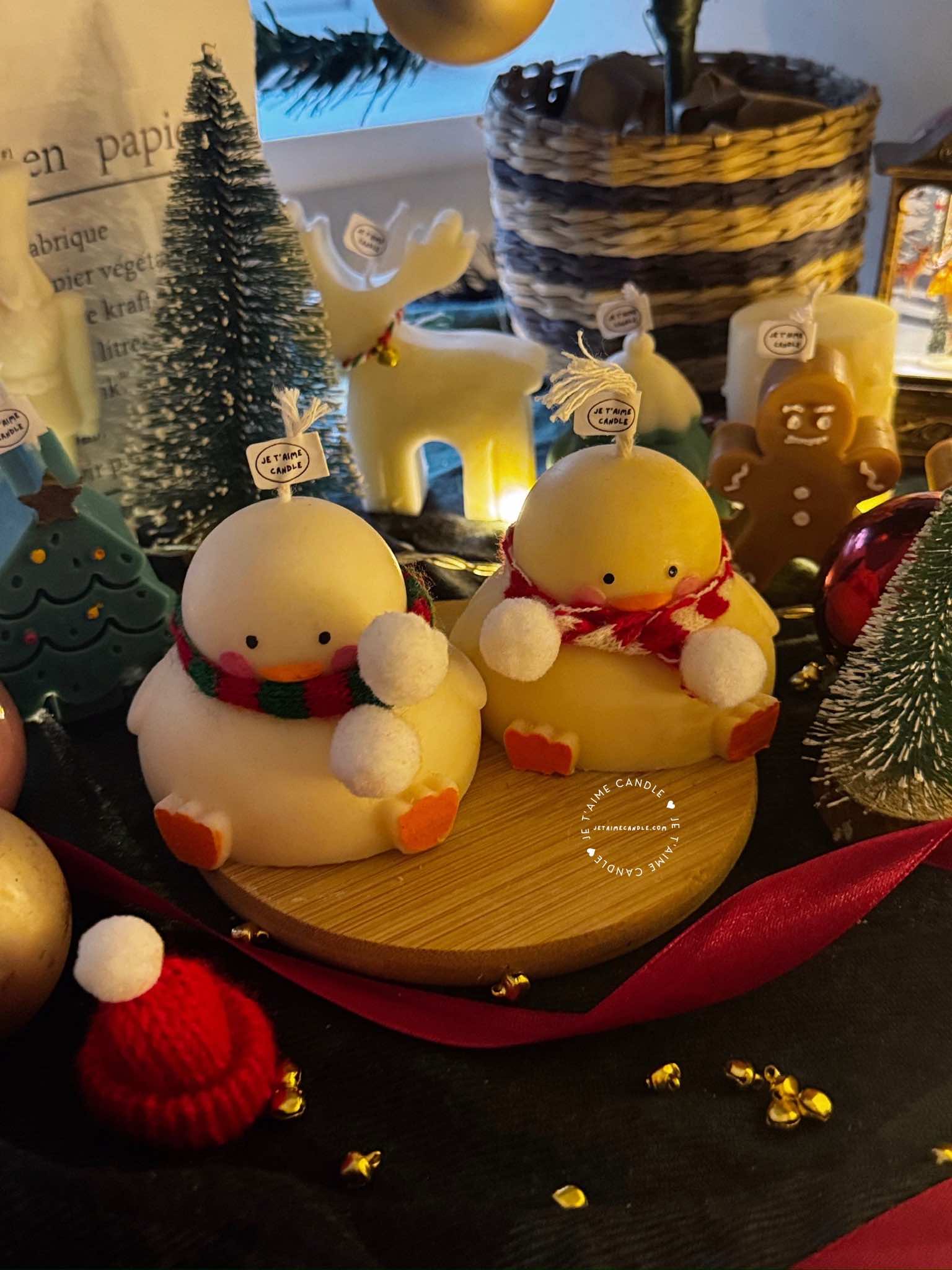 Two ducks in candle cozy scarves resting on a wooden board, ideal for unique holiday decor and gift inspiration.