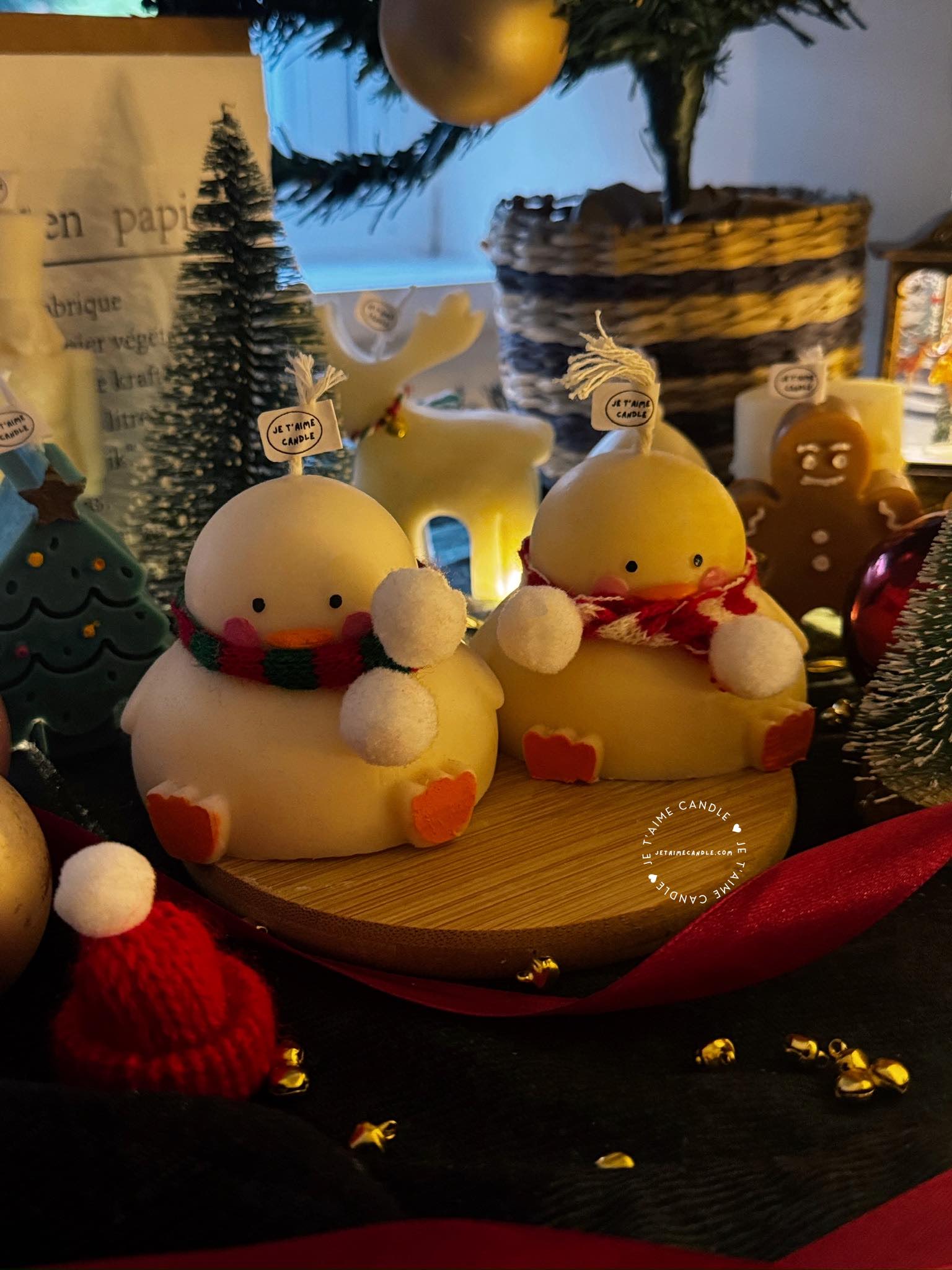 Two ducks in candle cozy scarves resting on a wooden board, ideal for unique holiday decor and gift inspiration.