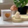 A table displaying unique animal-shaped candles and a book, perfect for enhancing the charm and coziness of any space.