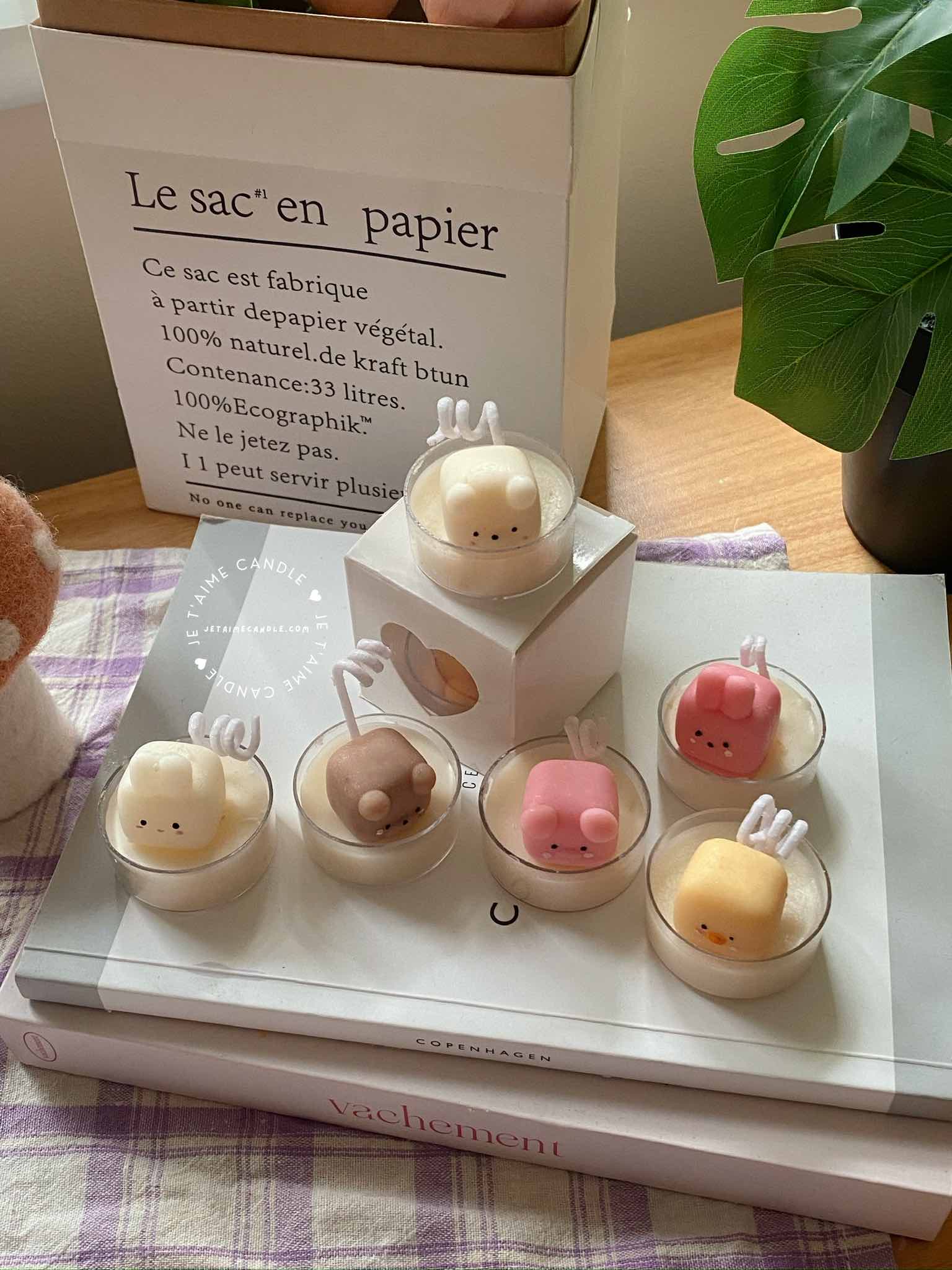 A table displaying unique animal-shaped candles and a book, perfect for enhancing the charm and coziness of any space.