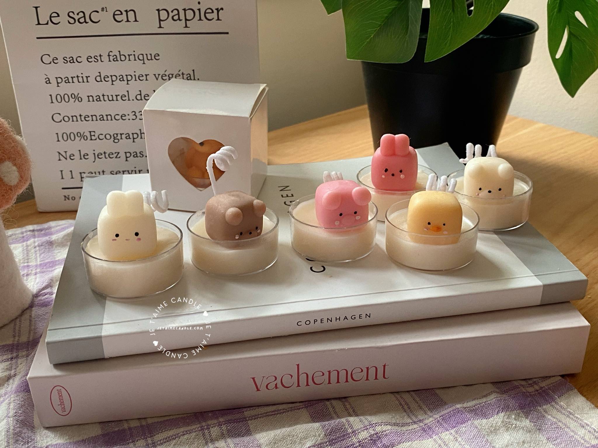 A table displaying unique animal-shaped candles and a book, perfect for enhancing the charm and coziness of any space.