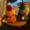 Two delightful toys in holiday-themed boxes, featuring Christmas decorations, including a Grumpy Cat Candle with a cozy hat.