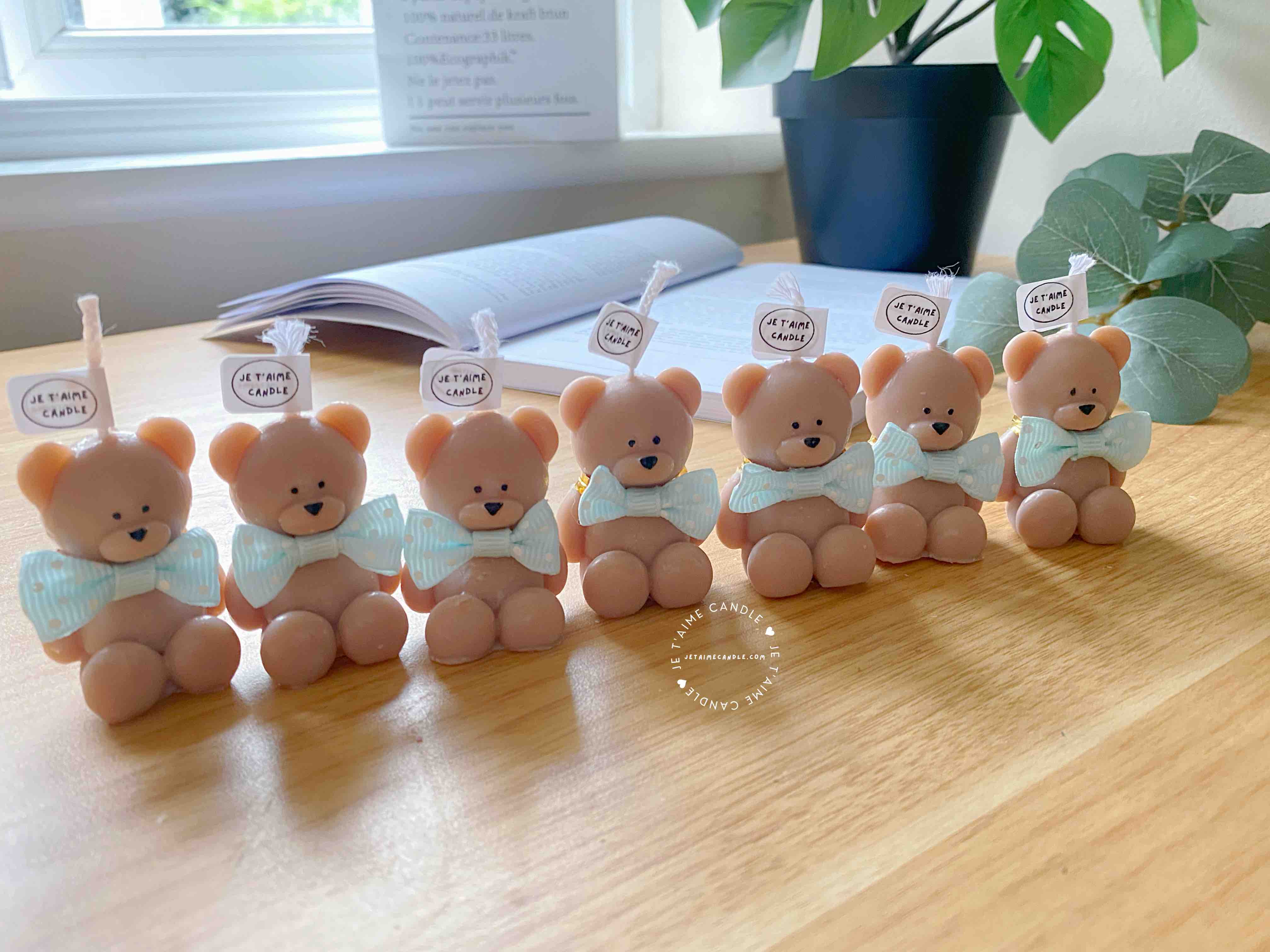 A delightful group of teddy bears on a table, showcasing the charm of our Handmade Mini Bear Candles in elegant bags.
