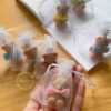 A delightful group of teddy bears on a table, showcasing the charm of our Handmade Mini Bear Candles in elegant bags.