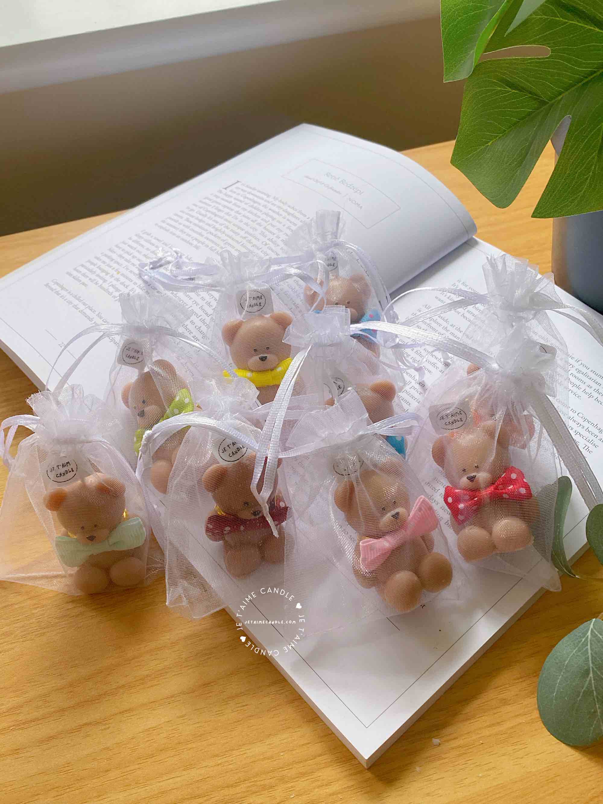 A delightful group of teddy bears on a table, showcasing the charm of our Handmade Mini Bear Candles in elegant bags.