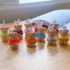 A delightful group of teddy bears on a table, showcasing the charm of our Handmade Mini Bear Candles in elegant bags.