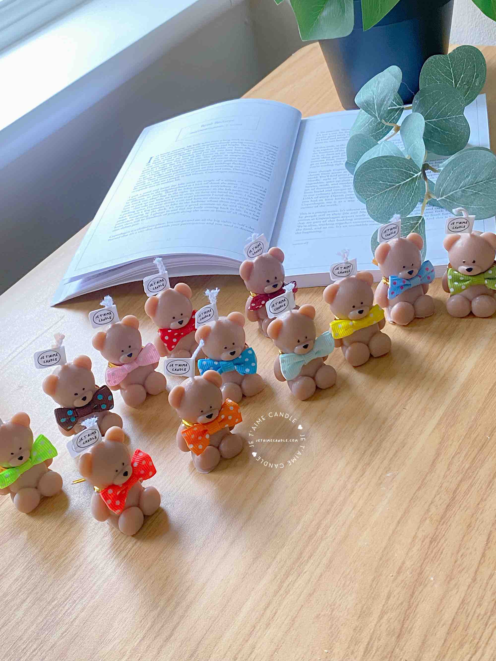 A delightful group of teddy bears on a table, showcasing the charm of our Handmade Mini Bear Candles in elegant bags.