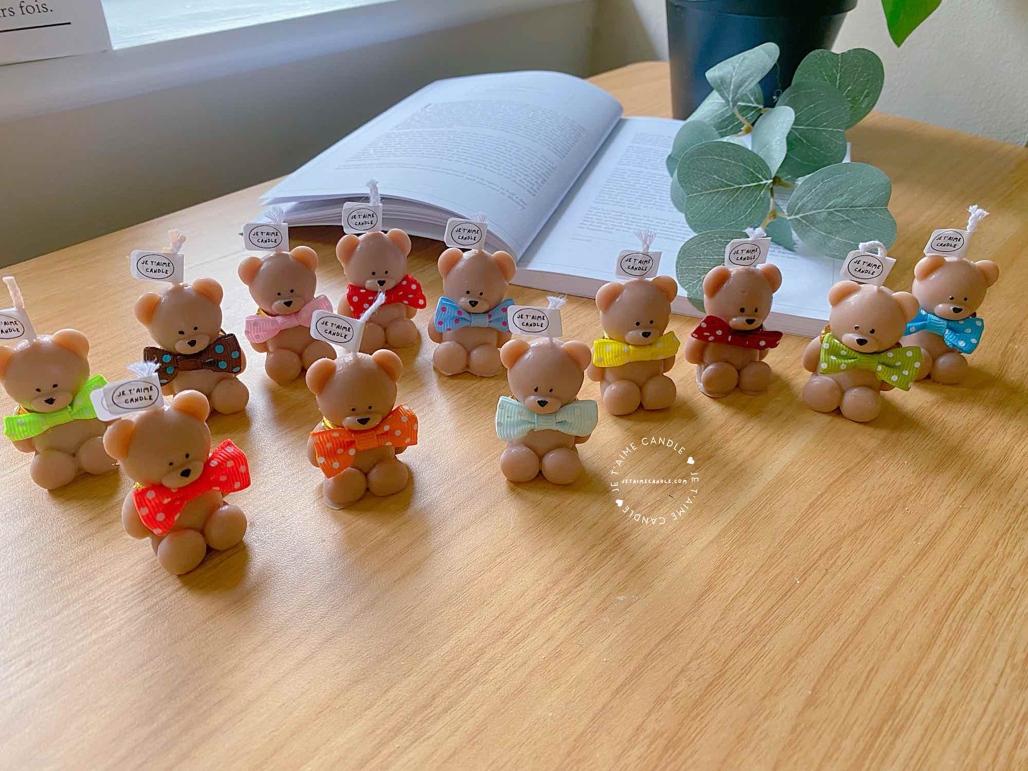 A delightful group of teddy bears on a table, showcasing the charm of our Handmade Mini Bear Candles in elegant bags.