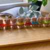 A delightful group of teddy bears on a table, showcasing the charm of our Handmade Mini Bear Candles in elegant bags.