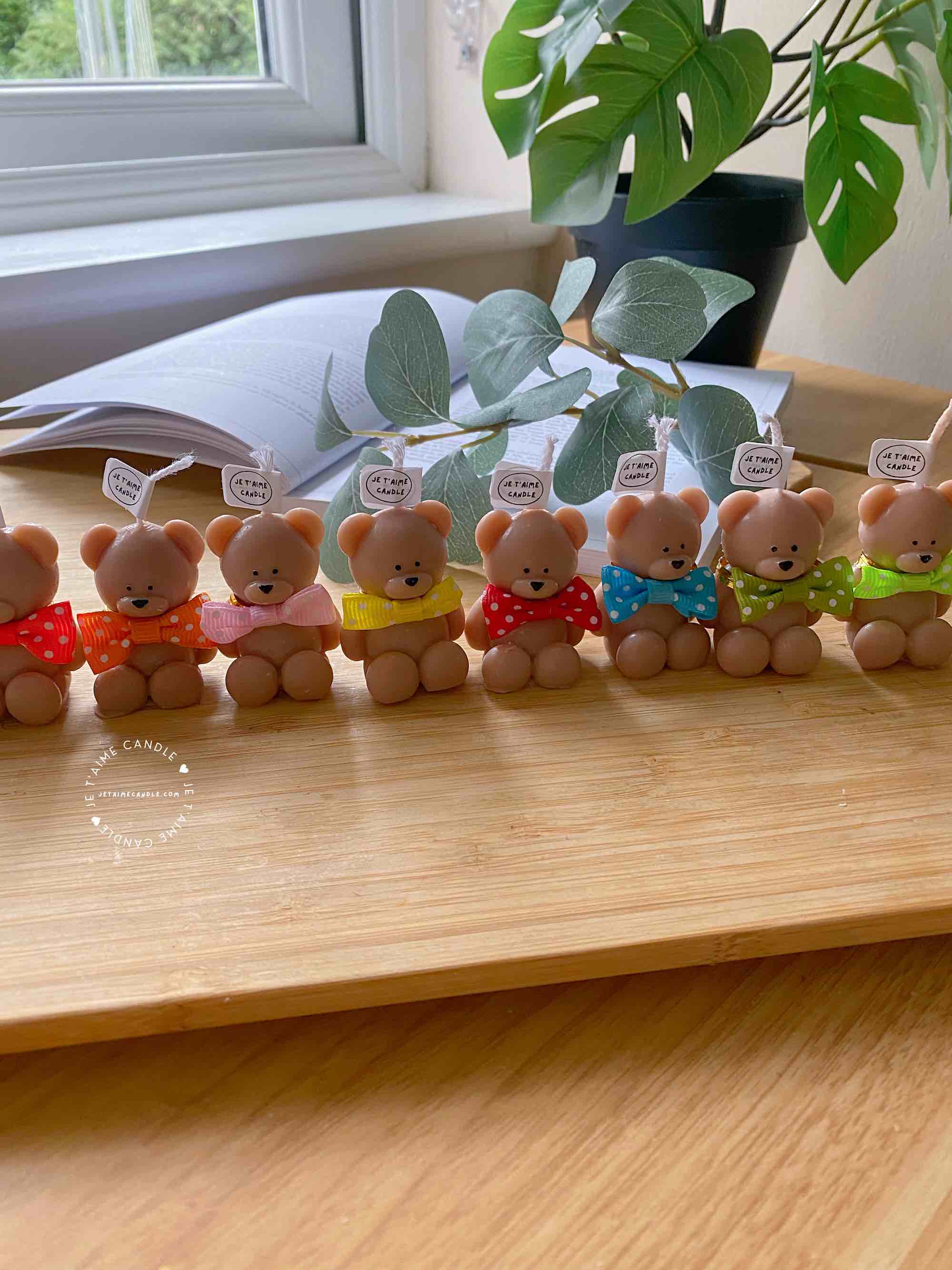 A delightful group of teddy bears on a table, showcasing the charm of our Handmade Mini Bear Candles in elegant bags.