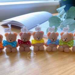 A delightful group of teddy bears on a table, showcasing the charm of our Handmade Mini Bear Candles in elegant bags.