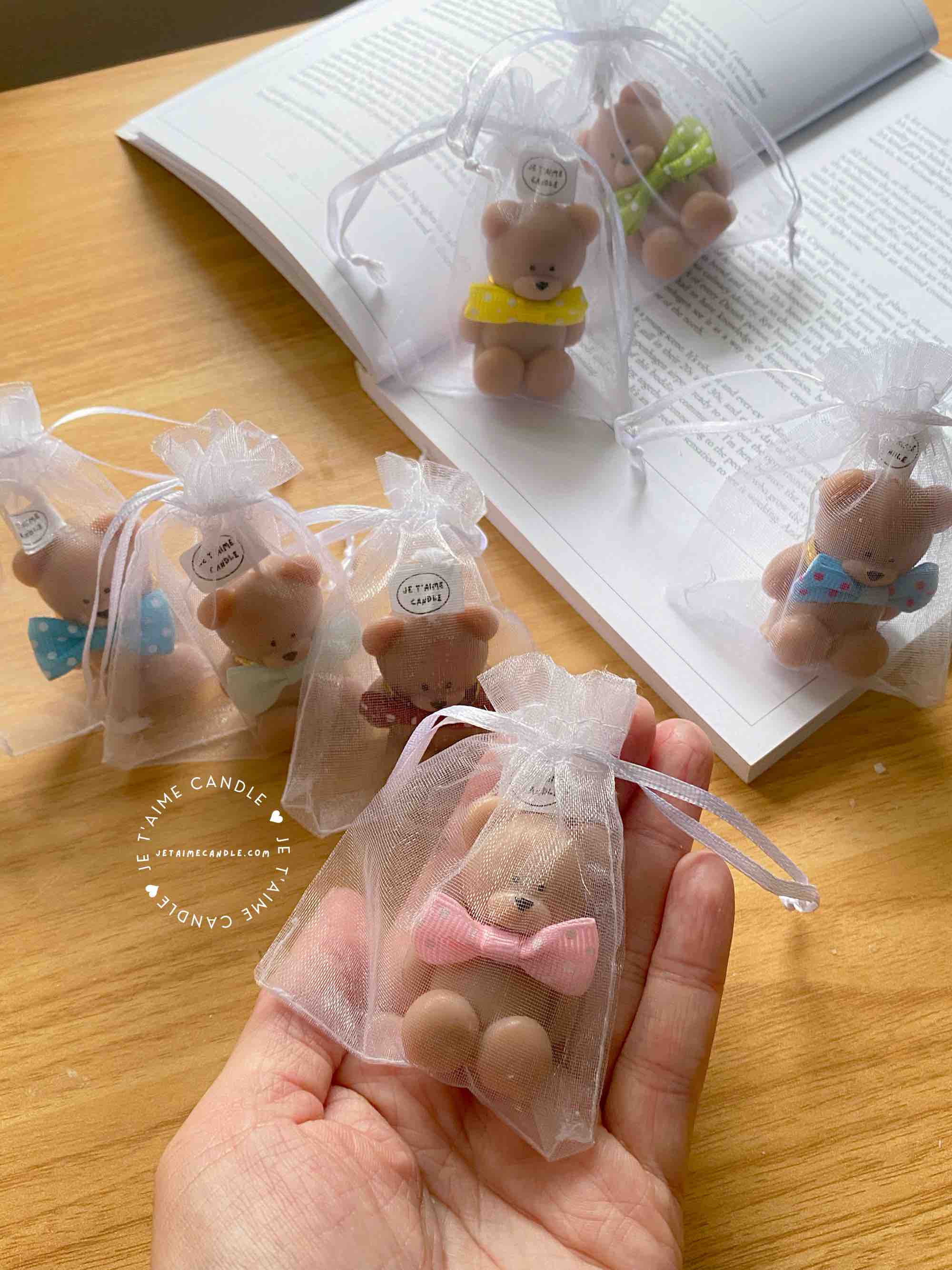 A delightful group of teddy bears on a table, showcasing the charm of our Handmade Mini Bear Candles in elegant bags.