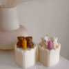Two small cream white cakes topped with cute baby bear decorations and a colorful birthday candle.