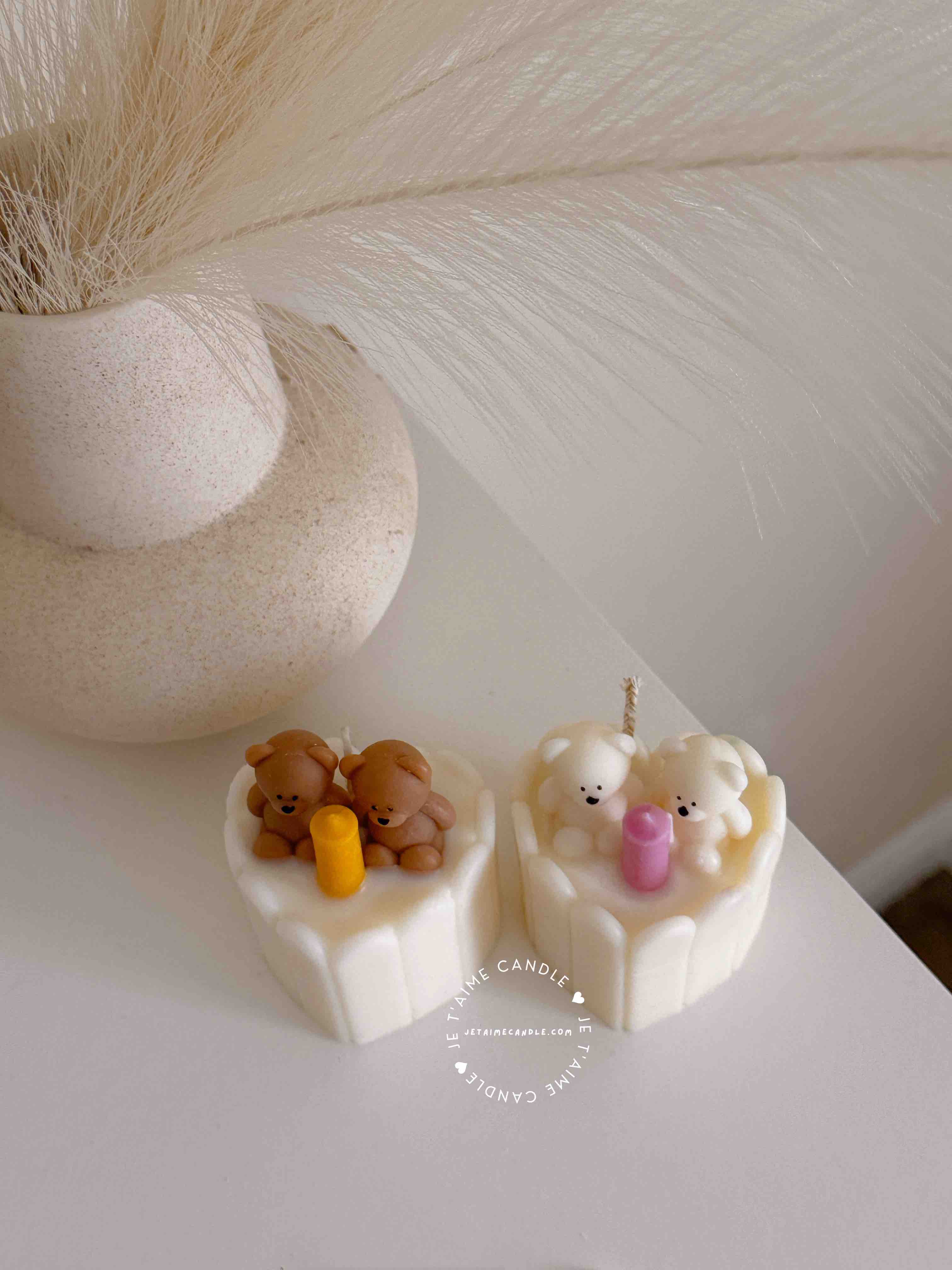 Two small cream white cakes topped with cute baby bear decorations and a colorful birthday candle.