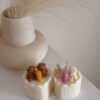 Two small cream white cakes topped with cute baby bear decorations and a colorful birthday candle.