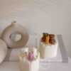 Two small cream white cakes topped with cute baby bear decorations and a colorful birthday candle.