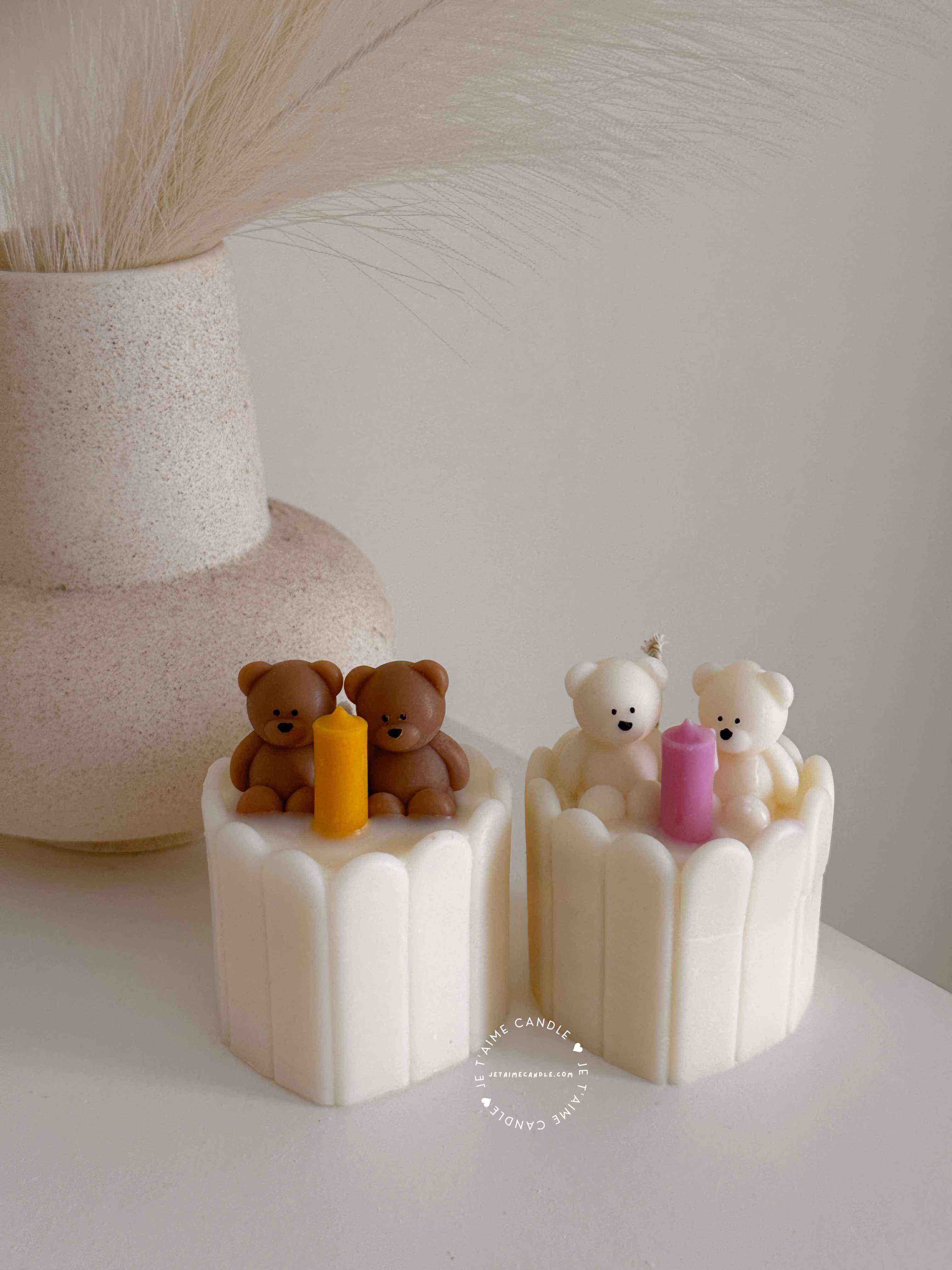 Two small cream white cakes topped with cute baby bear decorations and a colorful birthday candle.