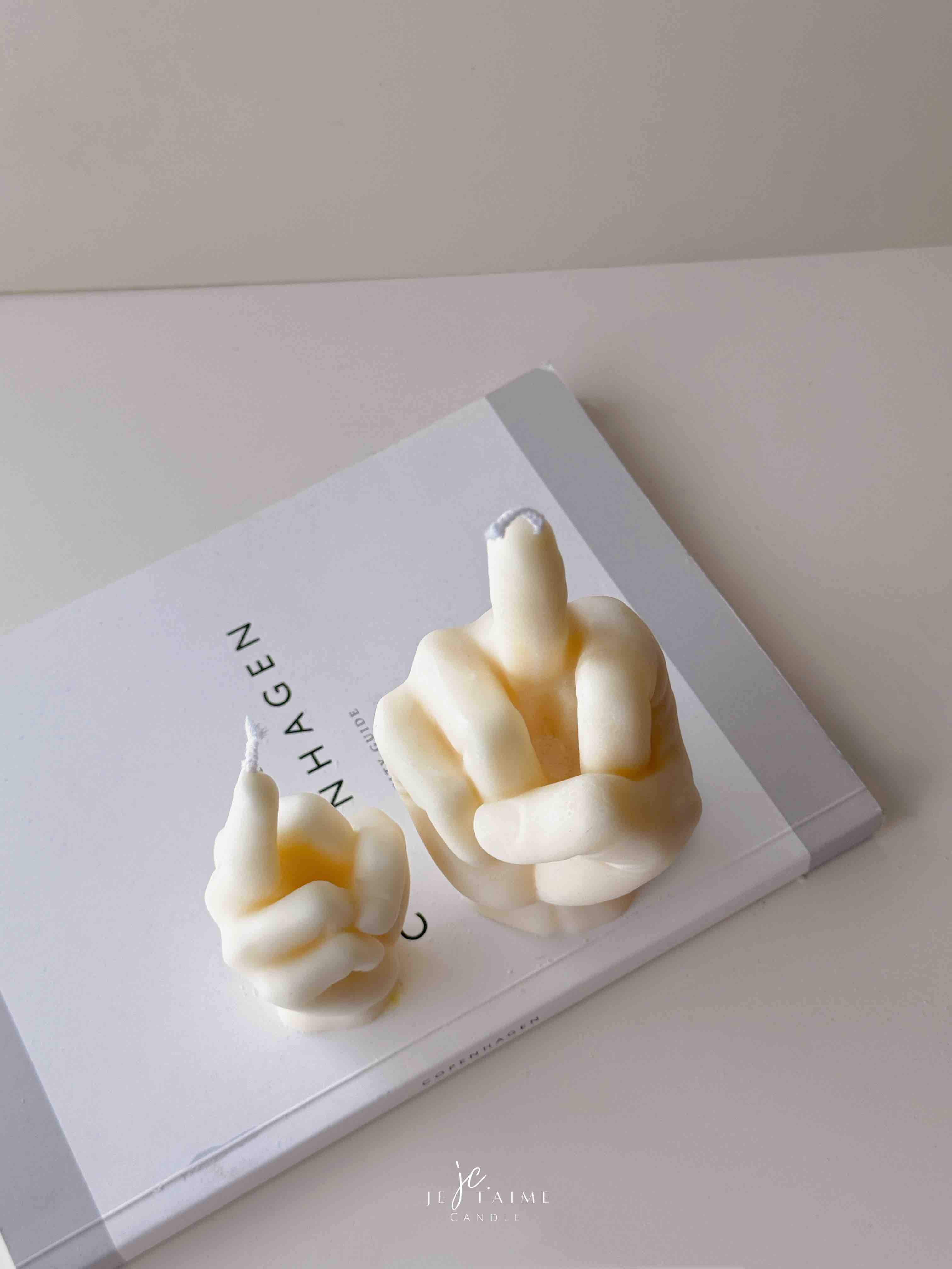 A row of multicolored candles shaped like hands making a gesture, lined up against a plain backdrop.