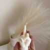 A row of multicolored candles shaped like hands making a gesture, lined up against a plain backdrop.