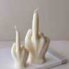 A row of multicolored candles shaped like hands making a gesture, lined up against a plain backdrop.