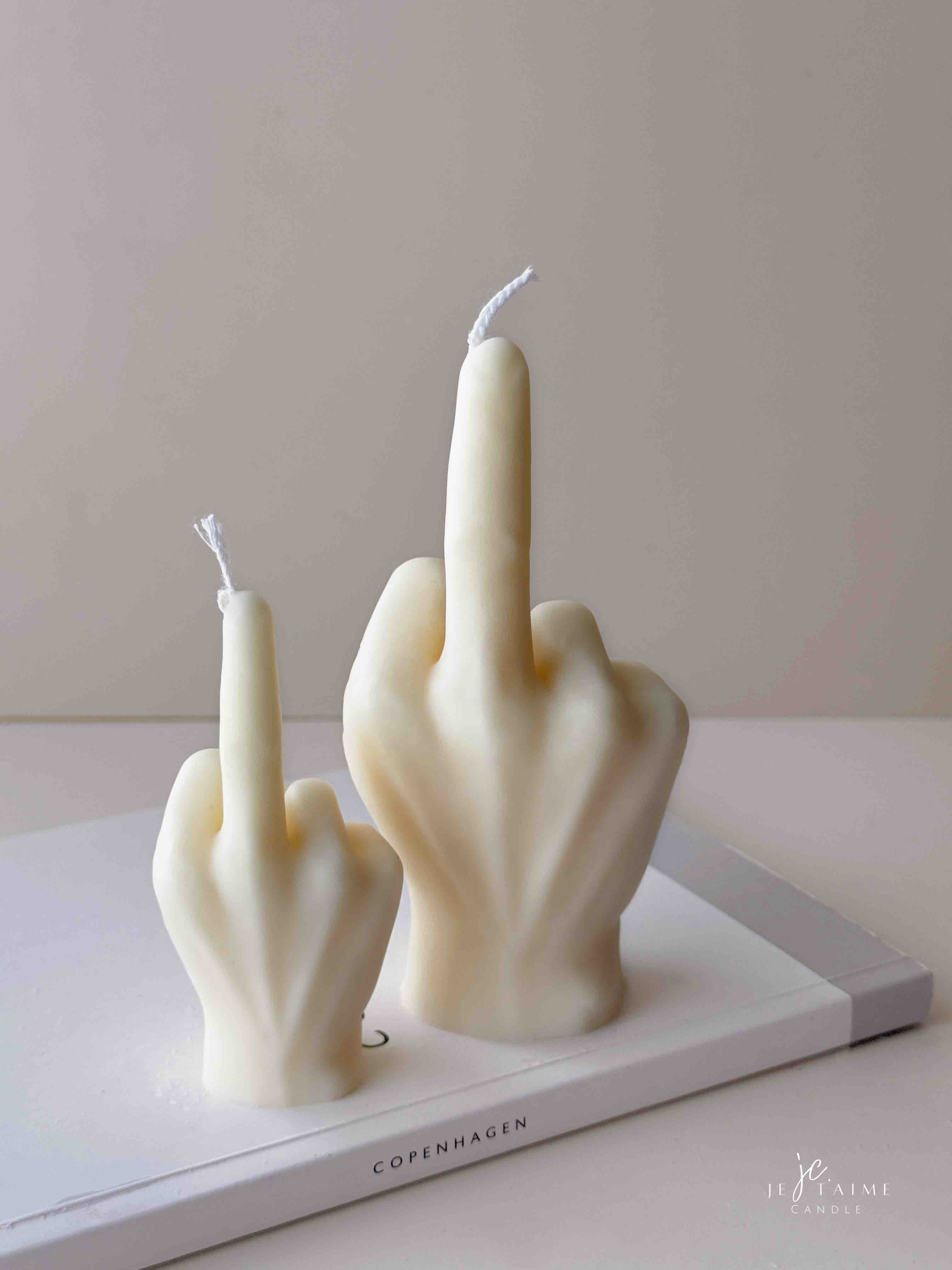 A row of multicolored candles shaped like hands making a gesture, lined up against a plain backdrop.