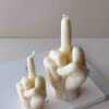 A row of multicolored candles shaped like hands making a gesture, lined up against a plain backdrop.