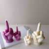 A row of multicolored candles shaped like hands making a gesture, lined up against a plain backdrop.
