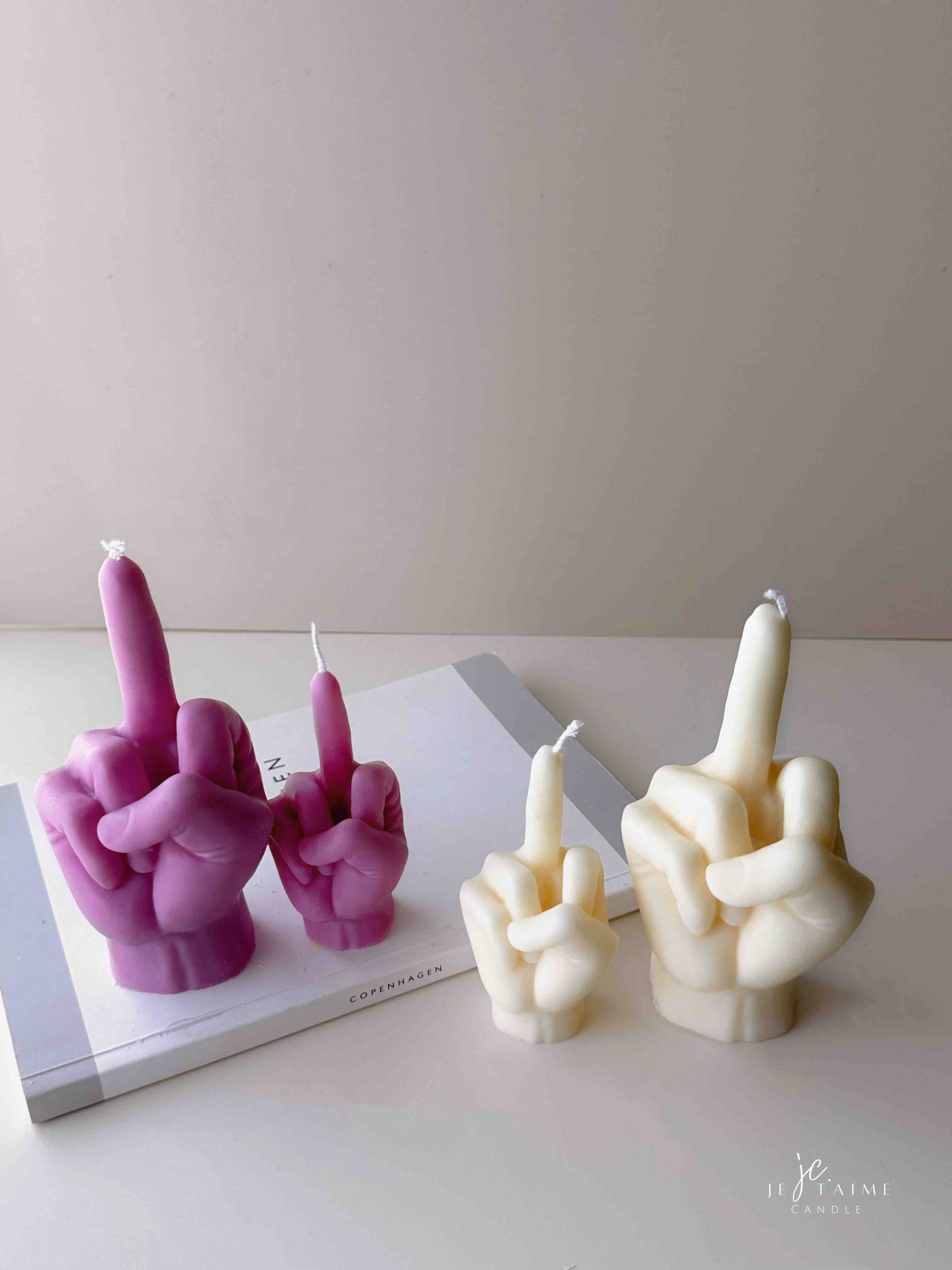 A row of multicolored candles shaped like hands making a gesture, lined up against a plain backdrop.