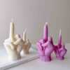 A row of multicolored candles shaped like hands making a gesture, lined up against a plain backdrop.