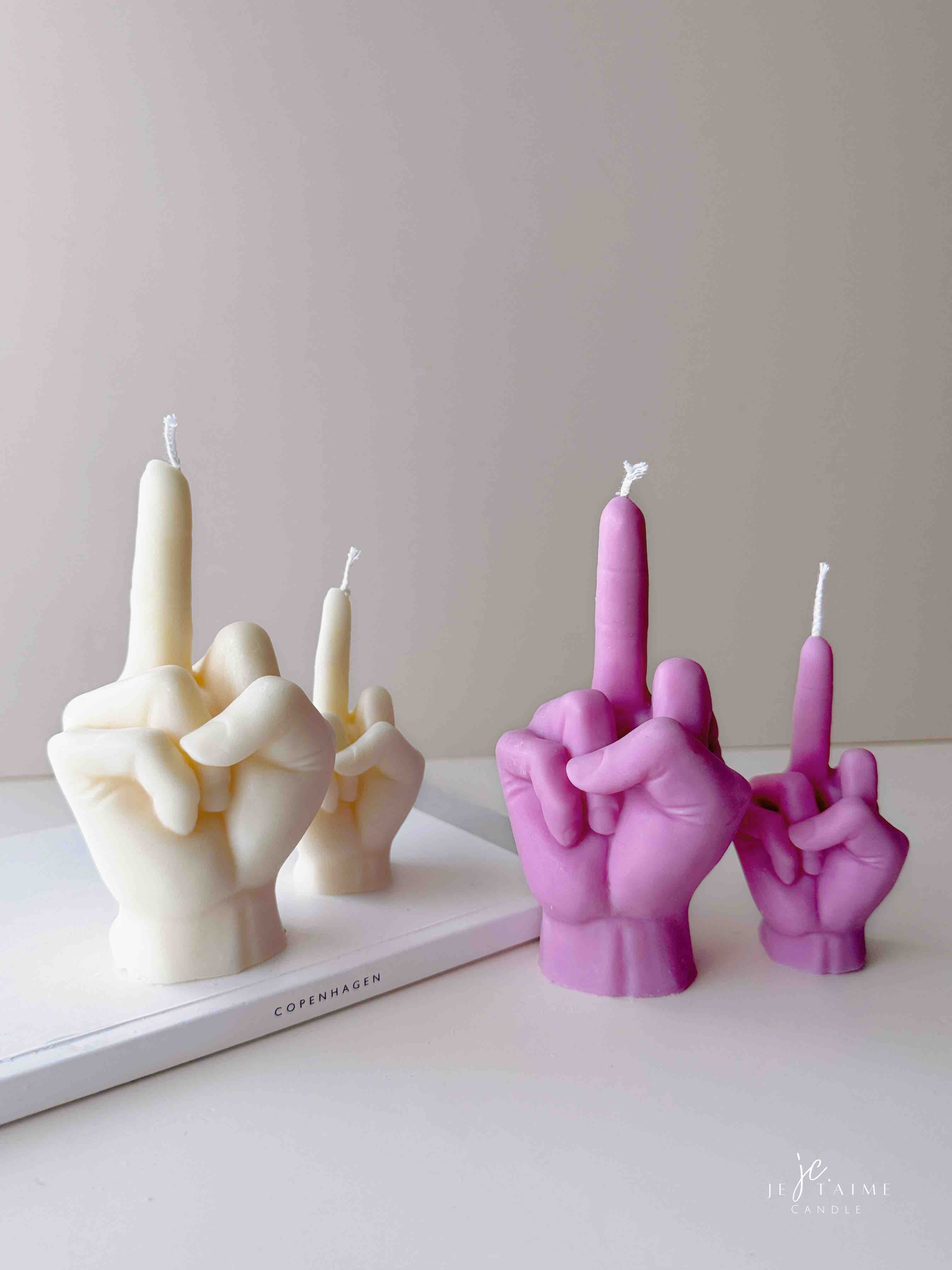 A row of multicolored candles shaped like hands making a gesture, lined up against a plain backdrop.