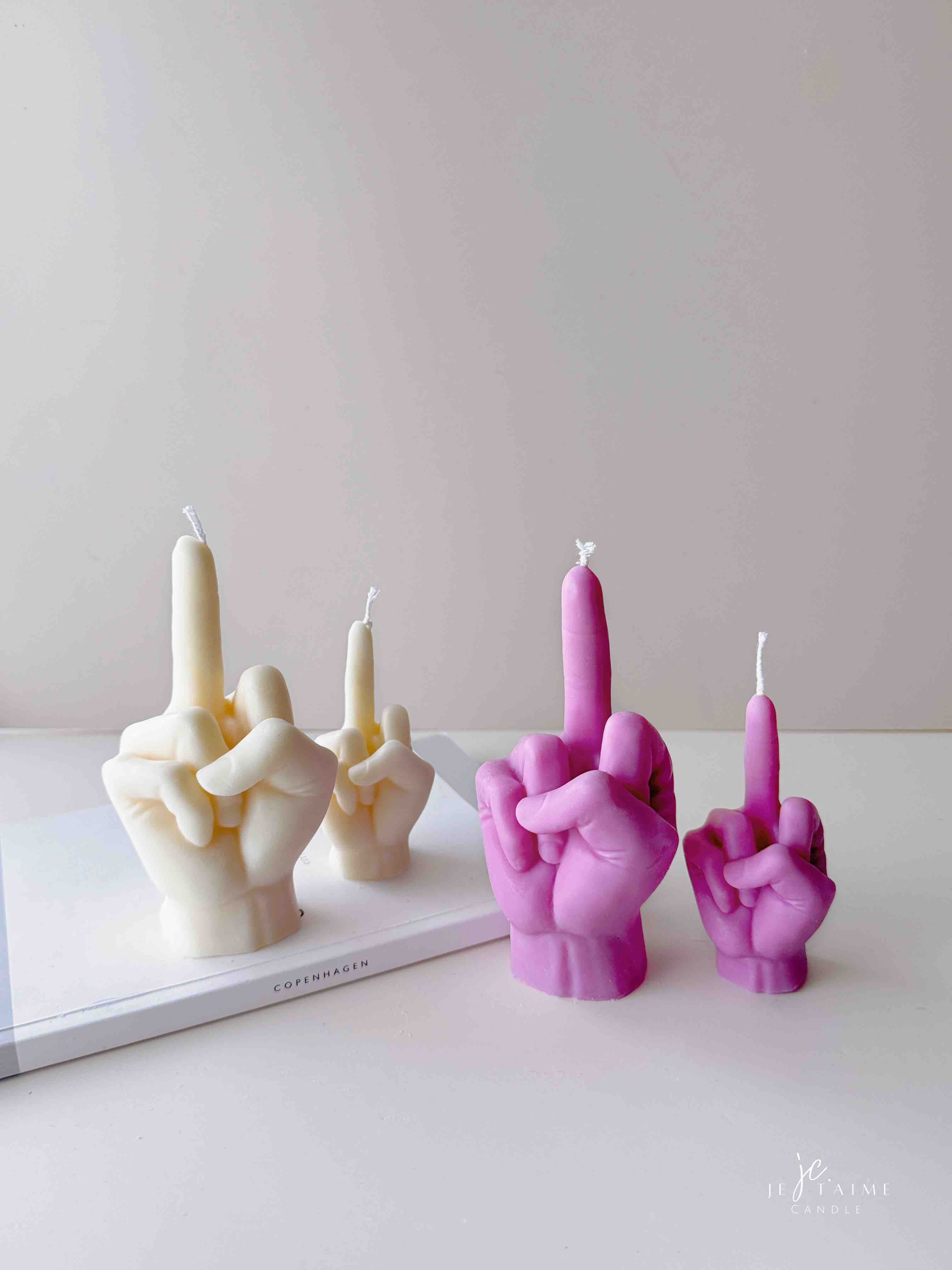 A row of multicolored candles shaped like hands making a gesture, lined up against a plain backdrop.