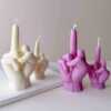 A row of multicolored candles shaped like hands making a gesture, lined up against a plain backdrop.