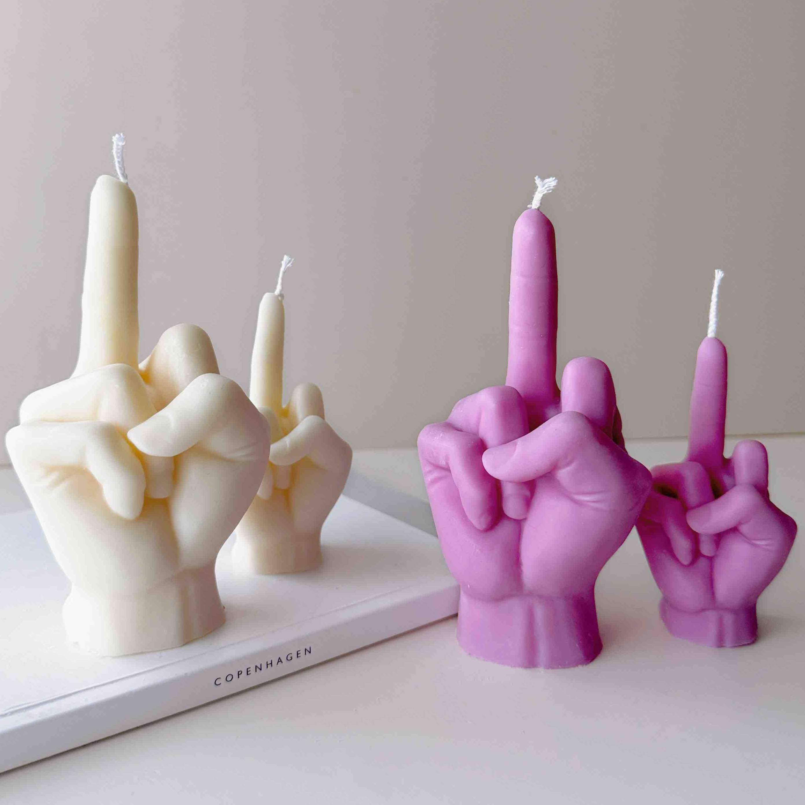 A row of multicolored candles shaped like hands making a gesture, lined up against a plain backdrop.