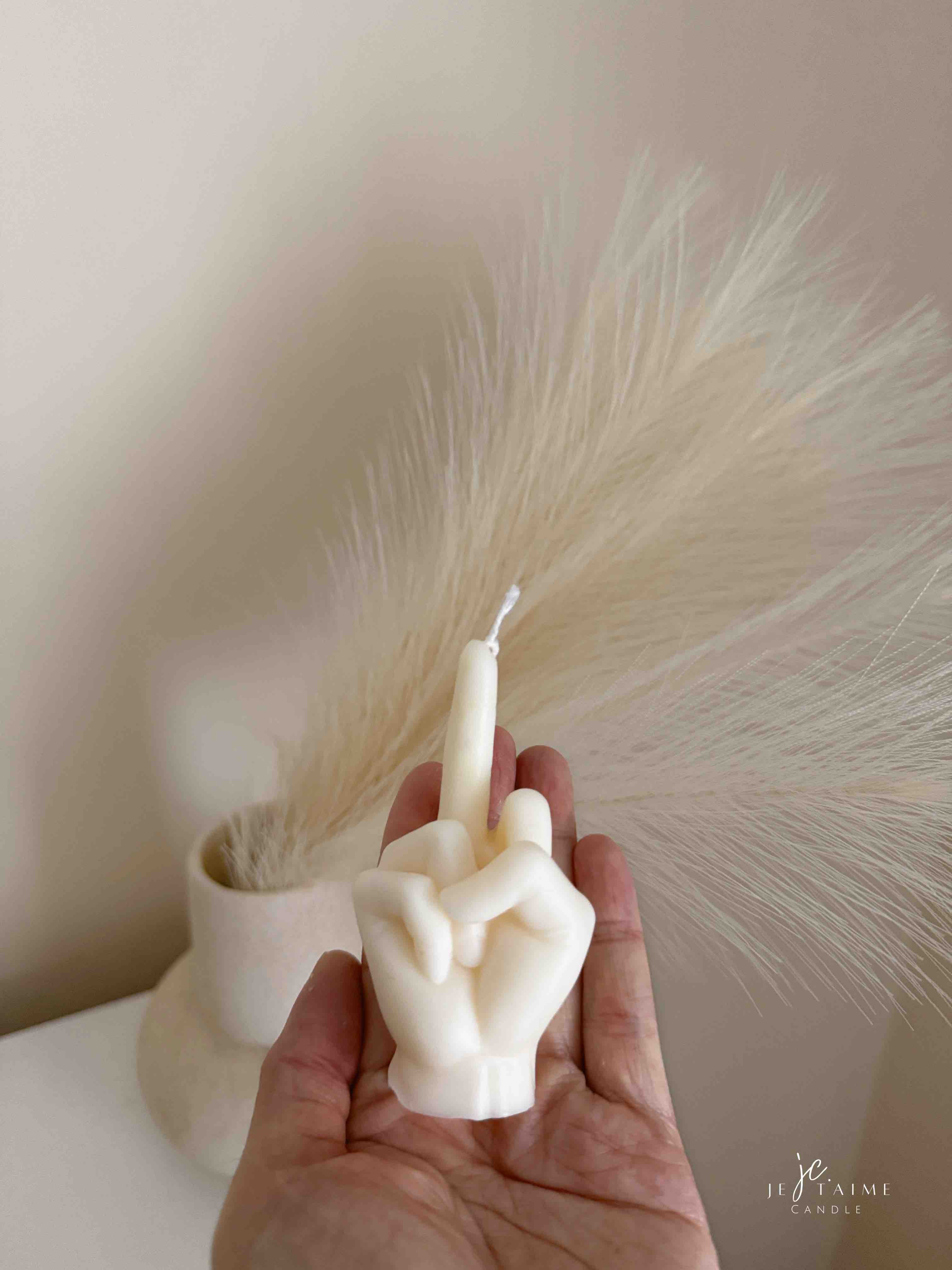 A row of multicolored candles shaped like hands making a gesture, lined up against a plain backdrop.