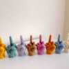 A row of multicolored candles shaped like hands making a gesture, lined up against a plain backdrop.