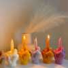 A row of multicolored candles shaped like hands making a gesture, lined up against a plain backdrop.