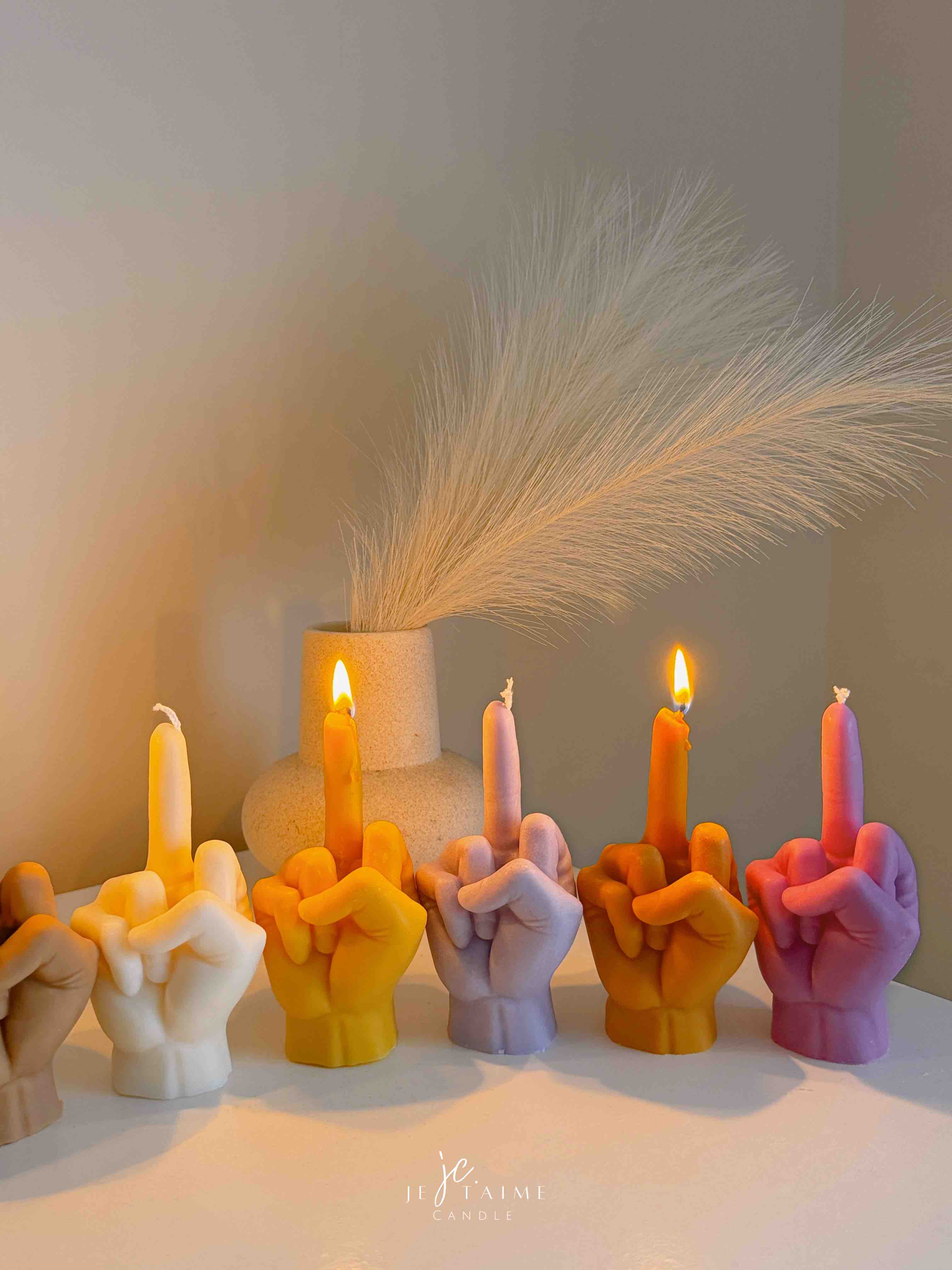 A row of multicolored candles shaped like hands making a gesture, lined up against a plain backdrop.