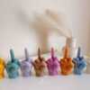 A row of multicolored candles shaped like hands making a gesture, lined up against a plain backdrop.