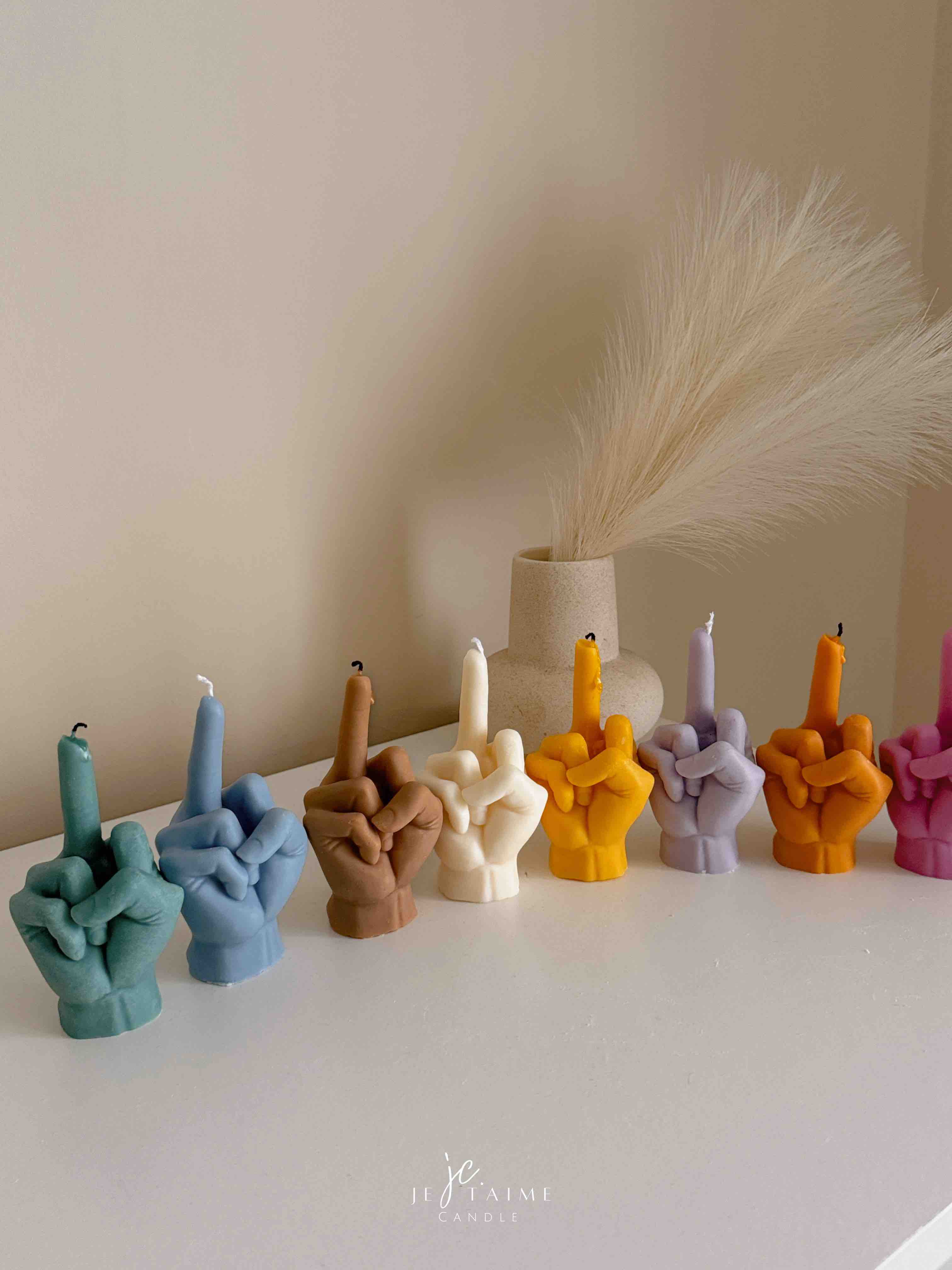 A row of multicolored candles shaped like hands making a gesture, lined up against a plain backdrop.