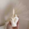 A row of multicolored candles shaped like hands making a gesture, lined up against a plain backdrop.
