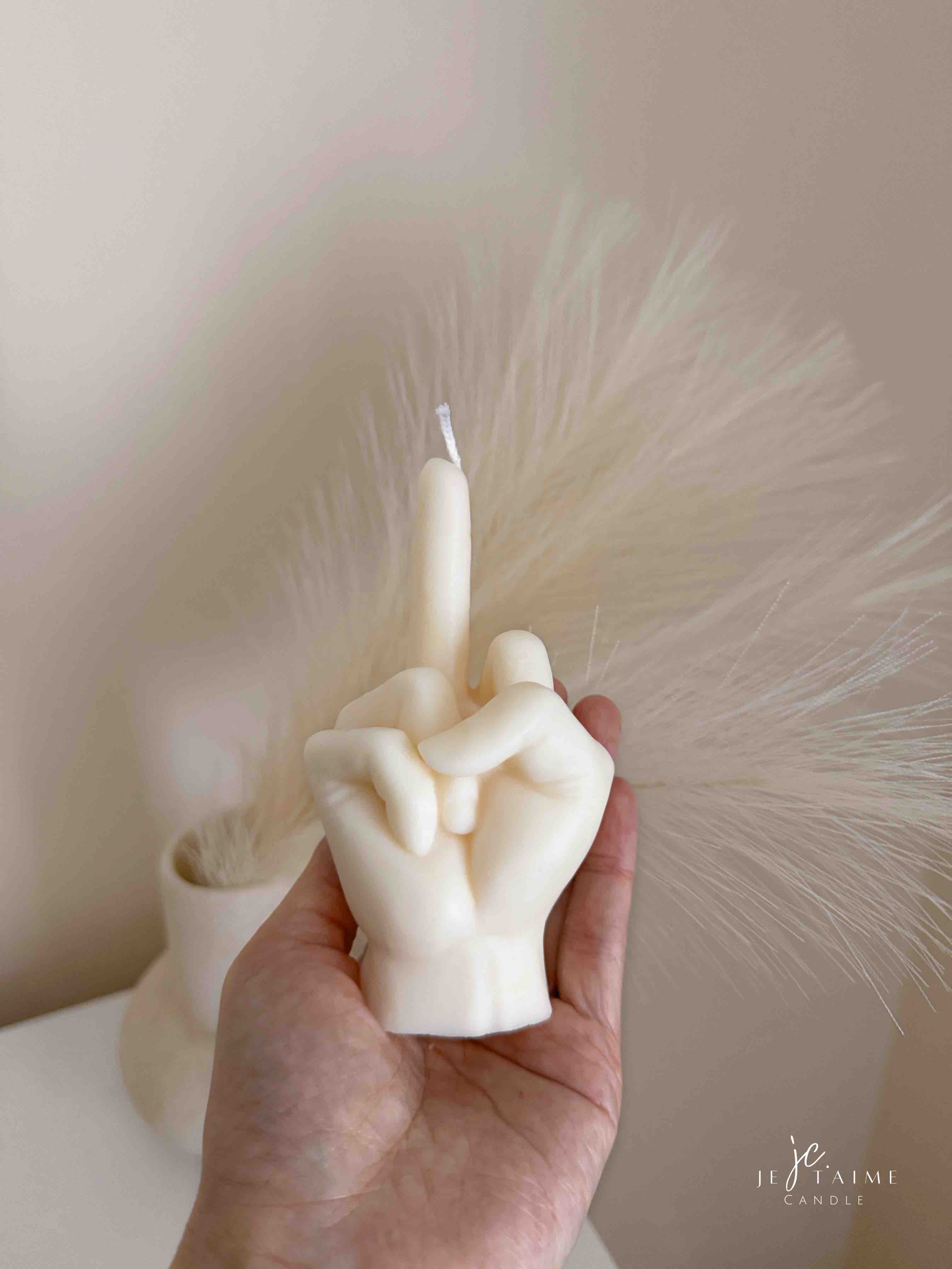 A row of multicolored candles shaped like hands making a gesture, lined up against a plain backdrop.